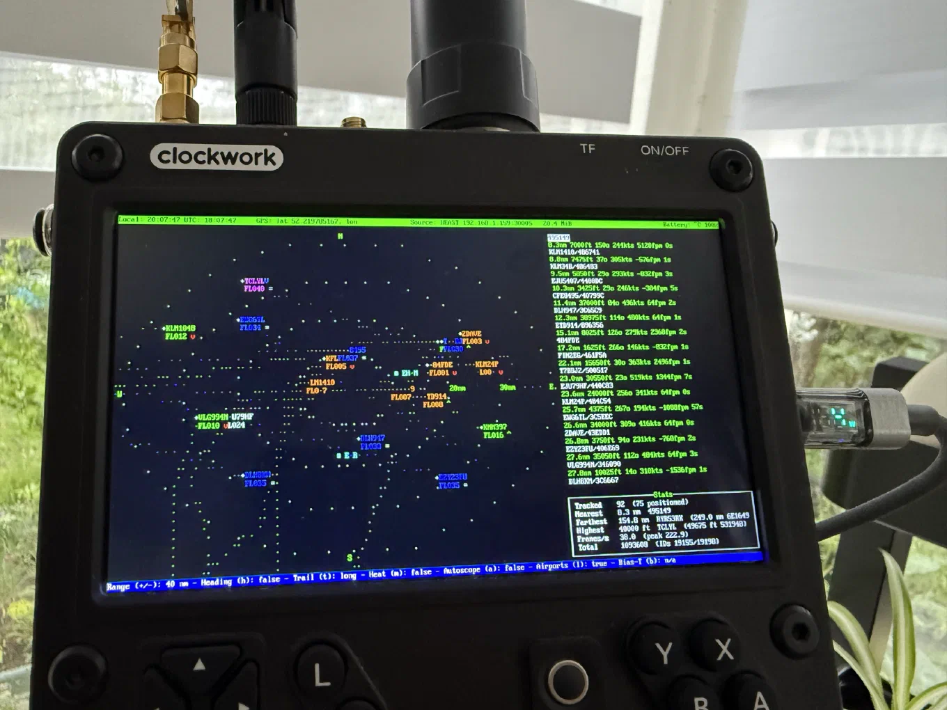 A ClockworkPi uConsole with two antennas screwed into the top, running uAirwaves on its built-in screen: a radar scope full of labelled aircraft, a distance-sorted list, and a stats panel reading 92 tracked, 75 positioned, farthest 154.8 nm.